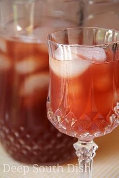 two glasses filled with liquid sitting next to each other on top of a tablecloth