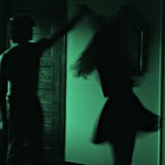 a woman standing next to a man in a dark room