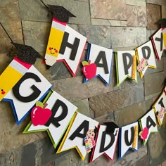 a graduation banner with the words congratulations on it and an apple in the middle, hanging from a brick wall