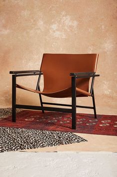 a brown leather chair sitting on top of a rug next to a wooden frame and black legs