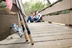 two people sitting on a bridge with fishing rods