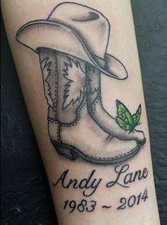 a tattoo on the leg of a person wearing cowboy boots and a hat with a green leaf