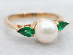 Add a touch of whimsy to your jewelry collection with our Yellow Gold Saltwater Pearl Ring. With elegant pear cut emerald accents, this ring is perfect for adding a pop of color to any outfit. Channel your inner mermaid with this playful and unique piece!Metal: 14K Yellow GoldGem: Saltwater PearlGem Measurements: 6.9 mm, RoundAccents: 2 Emeralds totaling .30 CaratsRing Size: 6Marks: "EH 14K" Stamped on the inside band College Rings, Dream Wedding Ring, Saltwater Pearls, Emerald Ring, Pear Cut, Pearl Ring, Unique Pieces, Gold Rings, Jewelry Collection