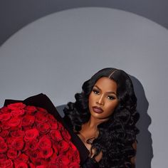 a woman holding a large bouquet of red roses