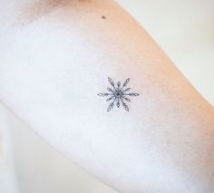 a small snowflake tattoo on the arm