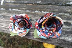 two flower brooches sitting on top of a wooden bench