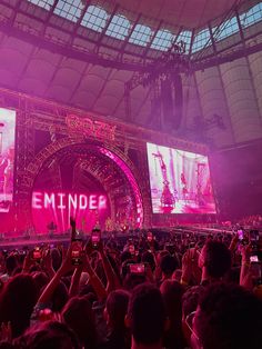 a large crowd at an outdoor concert taking pictures with their cell phones in front of the stage