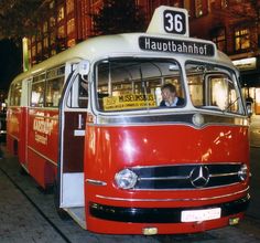 an old red and white bus is parked on the side of the street at night