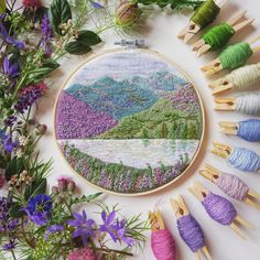 the embroidery project is being worked on with colorful thread and flowers in front of it