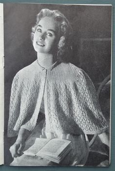 an old black and white photo of a woman holding a book