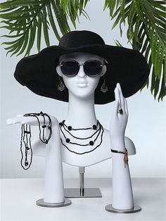 a mannequin wearing a black hat and sunglasses with jewelry on it's arms