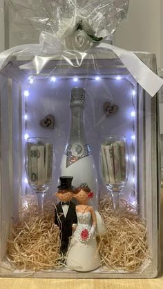 a wedding cake topper in a gift box with wine bottles and glasses on it