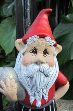 a statue of a gnome holding a ball in his hand and wearing a red hat