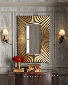 a large mirror sitting on top of a wooden cabinet next to a vase with flowers