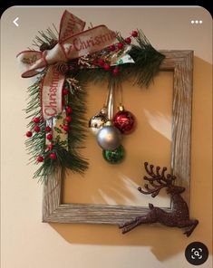 a christmas frame with ornaments hanging from it's sides and a reindeer ornament in the middle