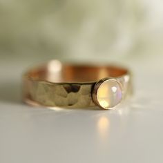 a close up of a gold ring with a white opal stone in the center