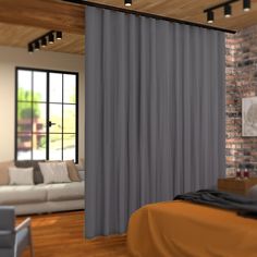 a living room with a brick wall and large window covered in grey drapes next to a white couch