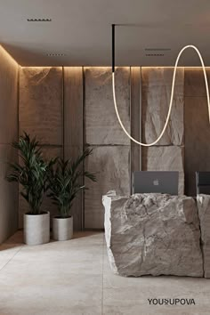 a stone desk with a laptop on it in front of a wall and planters