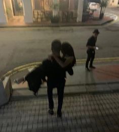 two people hugging each other on the sidewalk