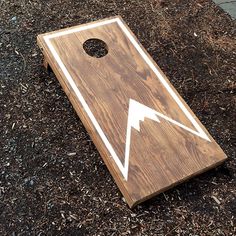 a cornhole board with an arrow painted on the side and wood chips scattered around it