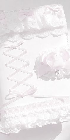 a white wedding garter with pink flowers and ribbons on the front, sitting on a white surface