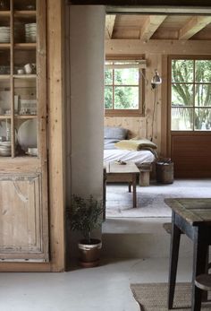 a room with wooden walls and shelves filled with dishes on top of each shelf next to a dining table