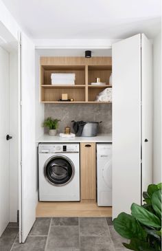 a washer and dryer in a small laundry room with open shelving on the wall