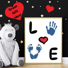 a teddy bear sitting next to a poster with handprints on it and hearts