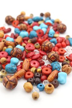 many beads are laying on top of each other in different shapes and colors, including red, orange, blue, and brown