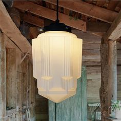 a white light hanging from the ceiling in a room with wooden walls and beams on it