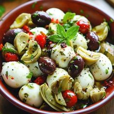 a close up of a bowl of food with olives, tomatoes and other vegetables