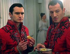 two men dressed in red are eating food