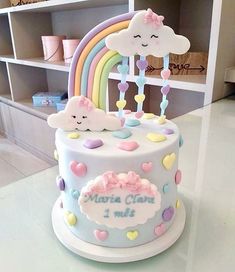 there is a birthday cake with clouds and rainbows on it