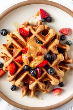 a waffle topped with fruit and syrup on a white plate