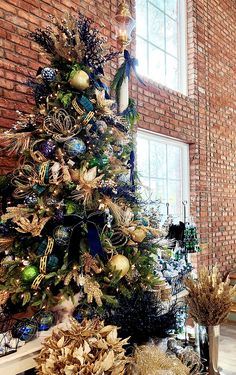 a decorated christmas tree in front of a brick wall with windows and other holiday decorations