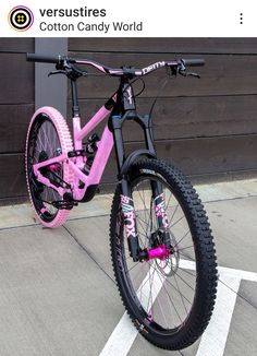 a pink and black bike parked in front of a wooden building with white lines on the ground