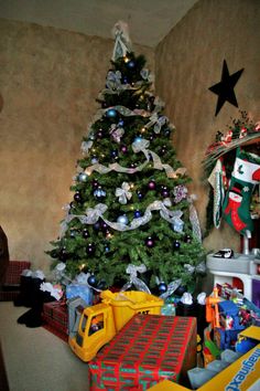 a christmas tree with presents under it in a room filled with toys and other items