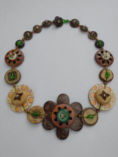 a necklace made out of buttons and other items on a white surface with a green bead