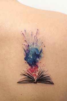 an open book tattoo on the back of a woman's shoulder