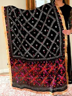 This traditional black silk phulkari gotta patti work dupatta is meticulously crafted with luxurious pure Chinon silk, featuring all over Gotta Patti hand embroidery and boasts a striking metallic gold trim along the border. This classic piece is perfect for celebrations such as weddings, sangeet, jaago, and chunni ceremonies. Effortlessly pair this dupatta with any color for an elegant contrast and make it an admirable present for birthdays or anniversaries. Material: Pure silk chinonWork: Silk Black Silk Fabric With Zari Embroidery, Black Silk Embroidered Saree Fabric, Black Silk Dupatta With Traditional Drape, Black Embroidered Silk Saree, Black Silk Embroidered Saree, Black Unstitched Silk Dupatta, Unstitched Black Silk Dupatta, Black Silk Dupatta With Zari Work, Black Silk Embroidered Fabric For Diwali