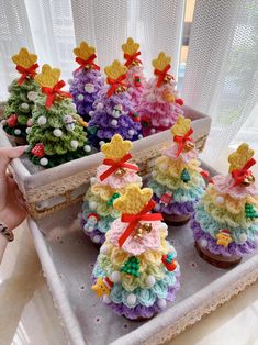 small crocheted christmas trees on a tray with cupcakes in the middle