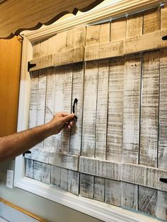 a man is holding a pair of scissors in front of an old wooden paneled wall