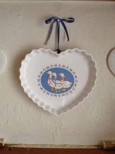 a white plate hanging on the wall with a blue bow around it's edge