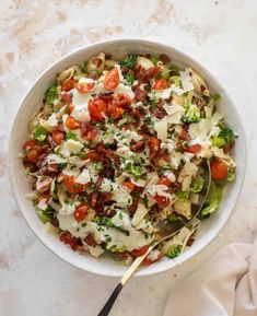 a white bowl filled with salad on top of a marble counter next to a spoon