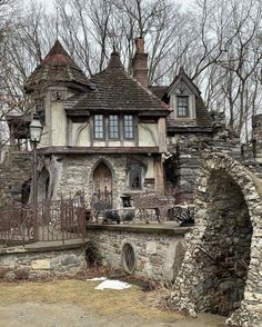 an old stone house in the woods with lots of windows and iron fencing around it