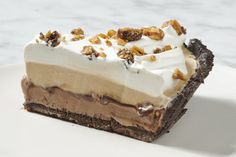 a piece of chocolate pie with whipped cream and walnuts on top is sitting on a white plate