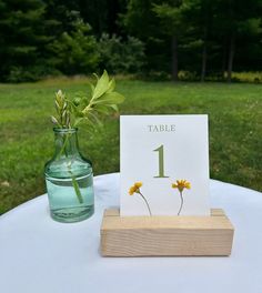 a table with a vase filled with yellow flowers and a card on top of it