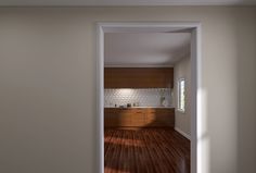 an open door leading to a kitchen with wood flooring and white brick wall in the background