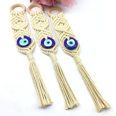 three macrame key chains with blue eyes and tassels on each one