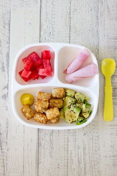 a white plate topped with food next to a yellow plastic fork and spoon on top of a wooden table